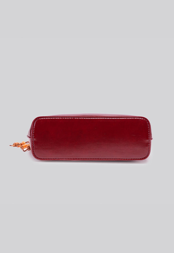 Glossy crescent hobo shoulder bag in deep burgundy with beaded wood tassel charm and gold-tone ring hardware, detail view 11