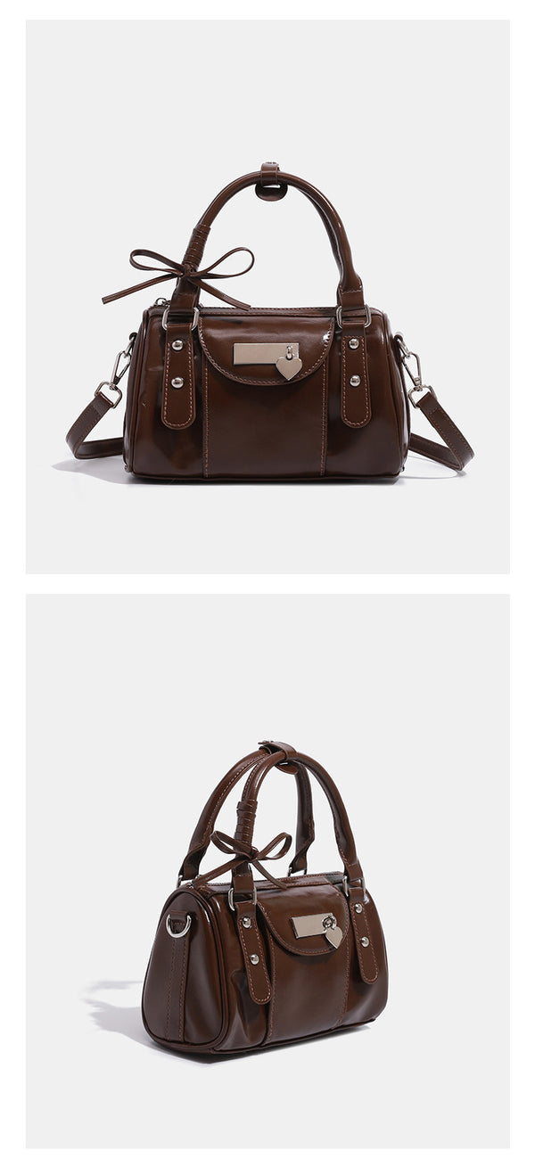 Kleine, formstabile Glanzledertasche mit zwei Henkeln, vorderer Klappentasche, herzförmigem Charm-Verschluss und silberfarbenem