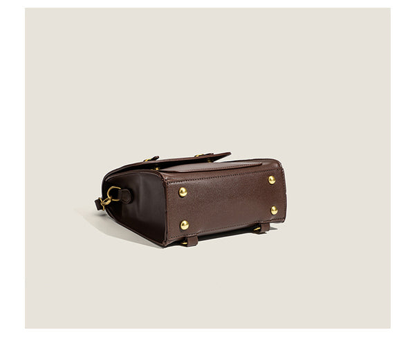 Structured mini satchel backpack with smooth leather-look finish, front flap pocket, gold-tone stud closures, and top handle