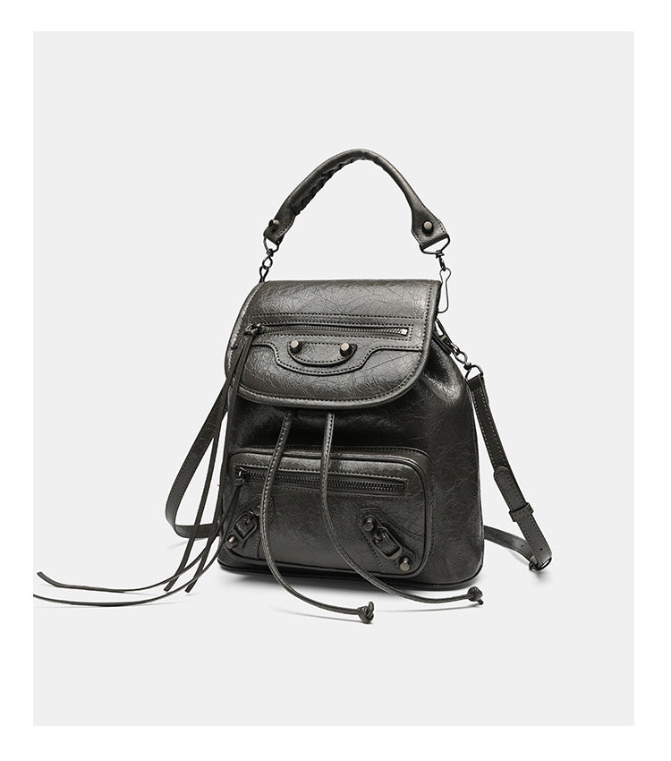 Small structured glossy leather-look convertible backpack handbag in black with flap closure, front zip pockets, metal stud