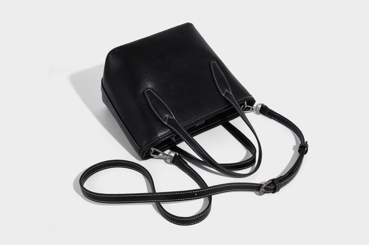 Compact structured bucket tote bag with pebbled textured finish, dual top handles, silver-tone lock hardware, and detachable