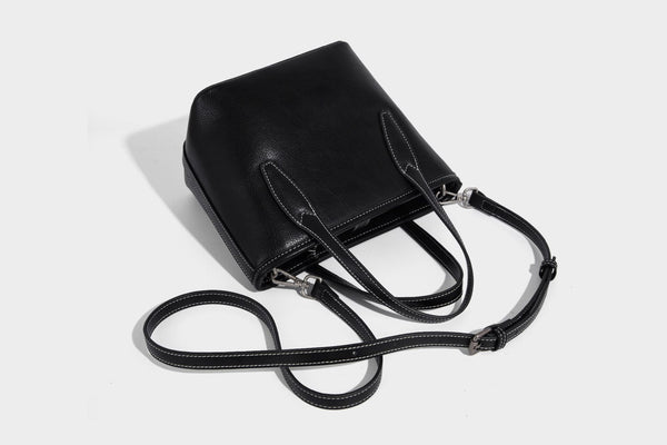 Compact structured bucket tote bag with pebbled textured finish, dual top handles, silver-tone lock hardware, and detachable