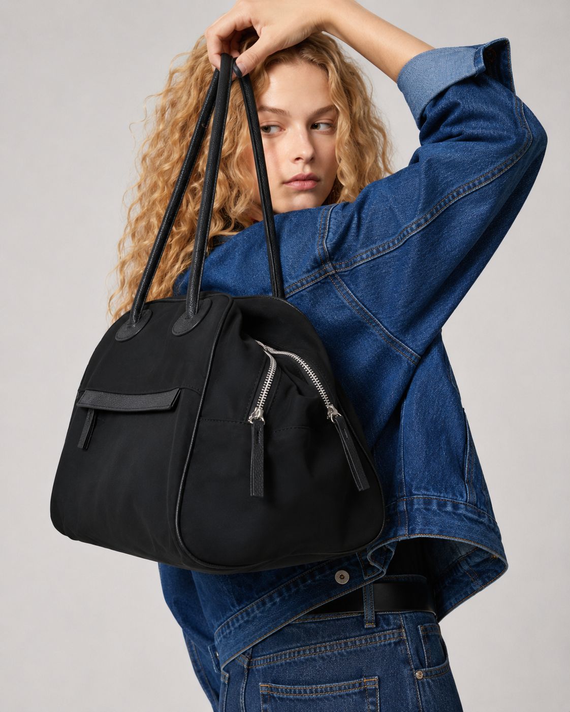 Structured dome top-handle bag in matte nylon with pebbled vegan leather-look trim, zip-top closure, front slip pocket, and