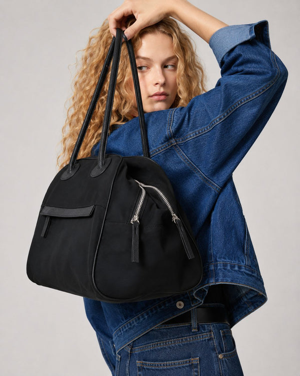 Structured dome top-handle bag in matte nylon with pebbled vegan leather-look trim, zip-top closure, front slip pocket, and