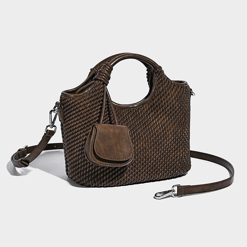Structured woven-texture bucket bag with knotted top handle, front flap pocket, and detachable silver-tone crossbody strap