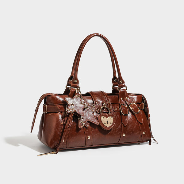 Glossy dark brown structured Boston satchel with heart-shaped lock charm, star pendant, rivet studs, multi-strap front panel