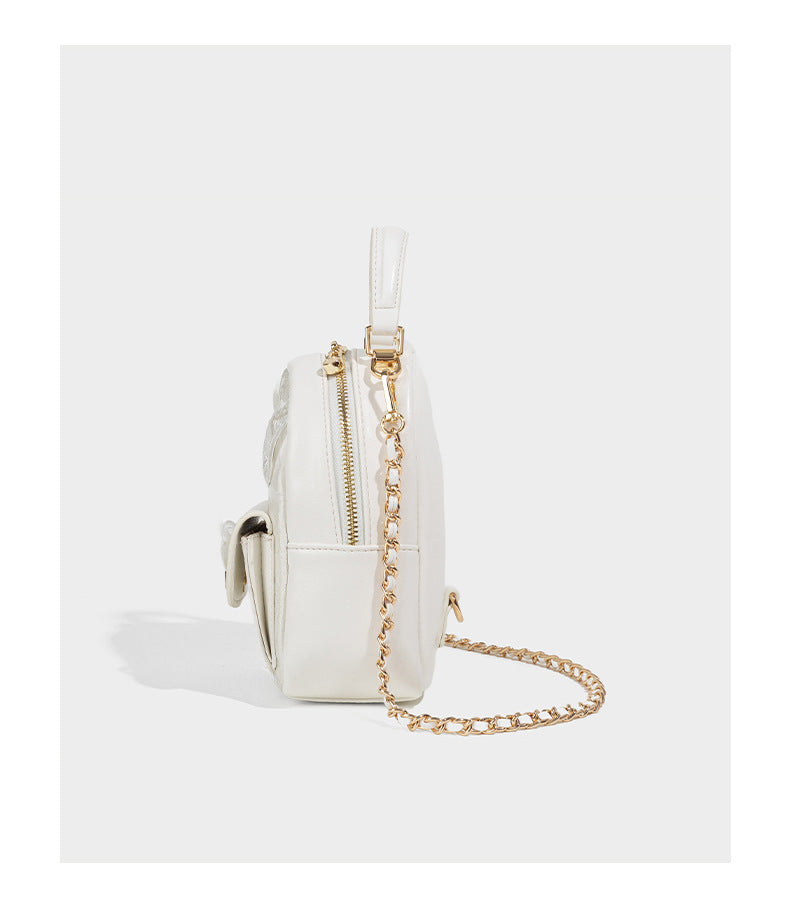Structured mini backpack handbag with butterfly embroidery, gold-tone chain strap, and turn-lock front flap pocket, detail