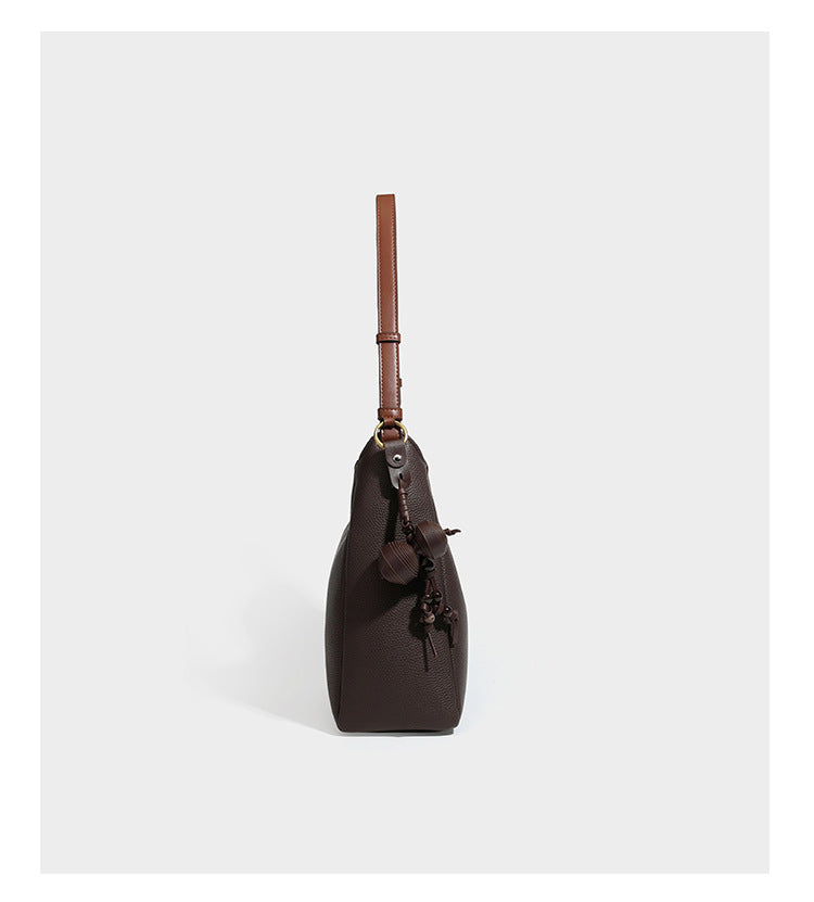 Hobo-Schultertasche in dunklem Espresso mit genarbter Oberfläche, warmen cognacfarbenen Details, verstellbarem schmalem Riemen, goldfarbenen Ringbeschlägen und geknotetem