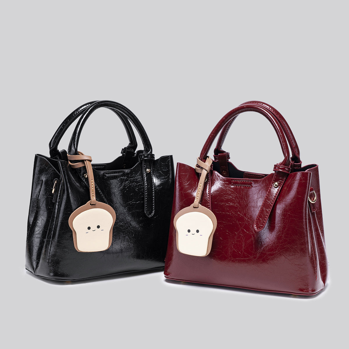 Structured glossy crinkled tote bag in burgundy red with gold-tone hardware, top handles, detachable shoulder strap, and