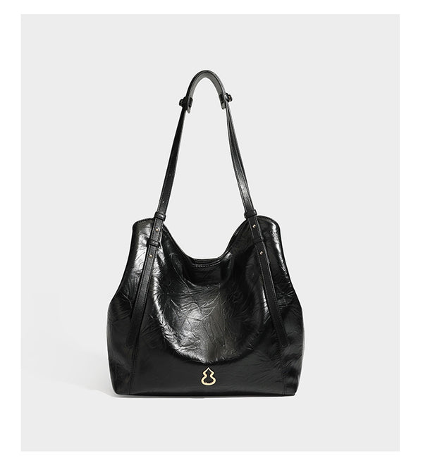 Große, glänzende Tote-Bag aus schwarzem Lederimitat mit geknitterter Optik, lässig fallender Trapezsilhouette, zwei Schulterriemen und goldfarbenen