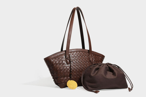 Large leather-look tote bag with geometric woven emboss, double shoulder straps, and round woven cord charm in brown, detail
