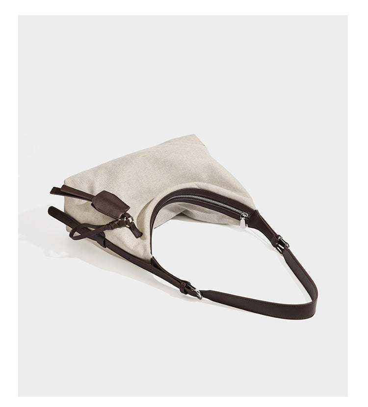 Cream canvas hobo shoulder bag with dark brown leather-look trim, zip-top closure, adjustable strap, and silver-tone