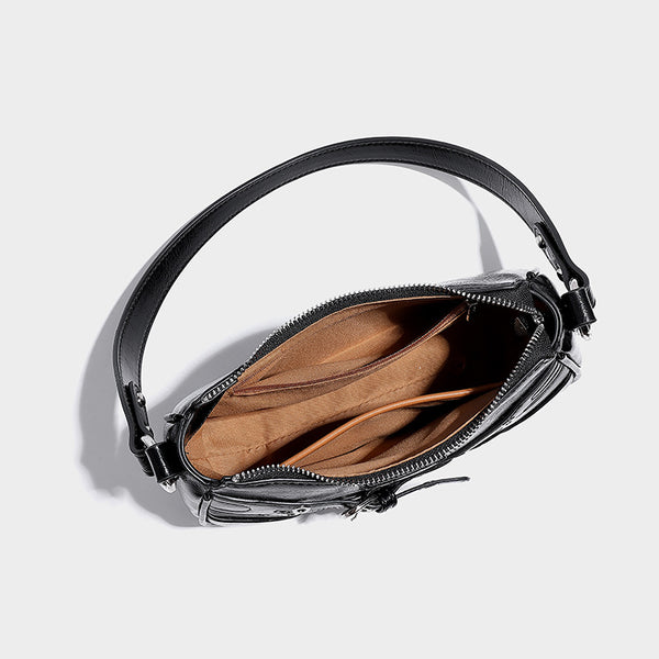 Compact moto-inspired shoulder bag with crisscross grommet strap detail, glossy textured finish, and adjustable crossbody