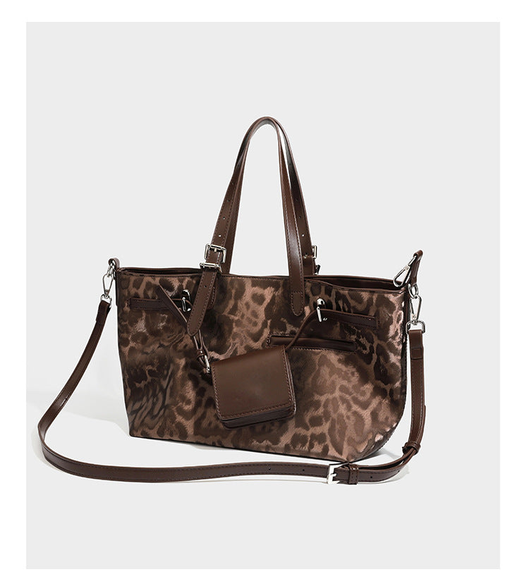 Glossy leopard-print tote bag with leather-look dark trim, dual top handles, detachable shoulder strap, and attached front
