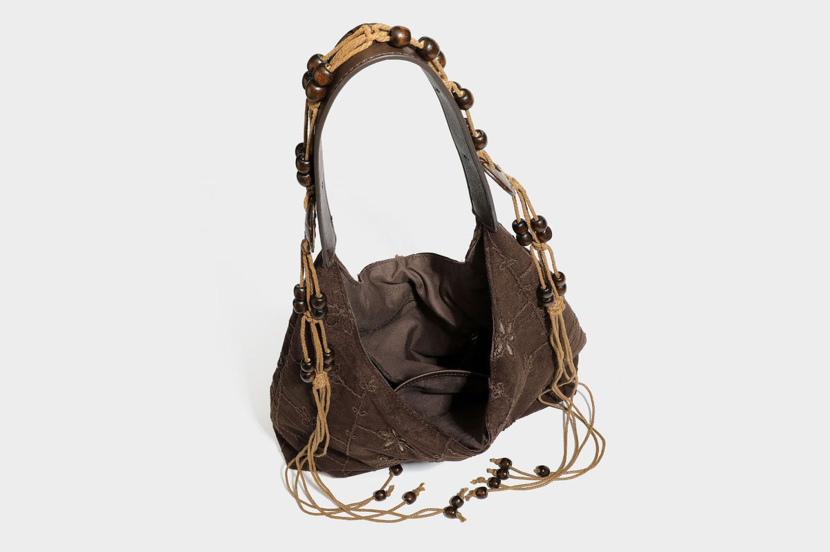 Dunkelbraune bestickte Hobo-Shopper-Tasche mit perlenverziertem Schulterriemen in Lederoptik, verknoteten Quastenbändern und ovalen Ringbeschlägen