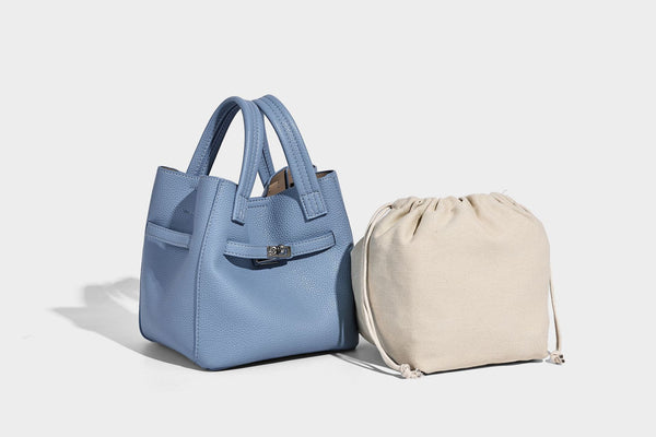 Small structured pebbled bucket tote bag with dual top handles, silver turn-lock front pocket, and detachable shoulder strap