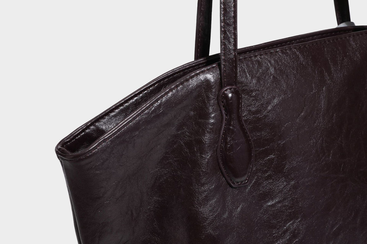 Übergroße, lässig fallende Tote-Bag aus glänzendem, geknittertem Lederimitat in dunklem Burgunderrot mit zwei langen Schulterriemen und kontrastierendem