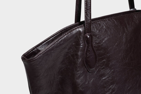 Übergroße, lässig fallende Tote-Bag aus glänzendem, geknittertem Lederimitat in dunklem Burgunderrot mit zwei langen Schulterriemen und kontrastierendem