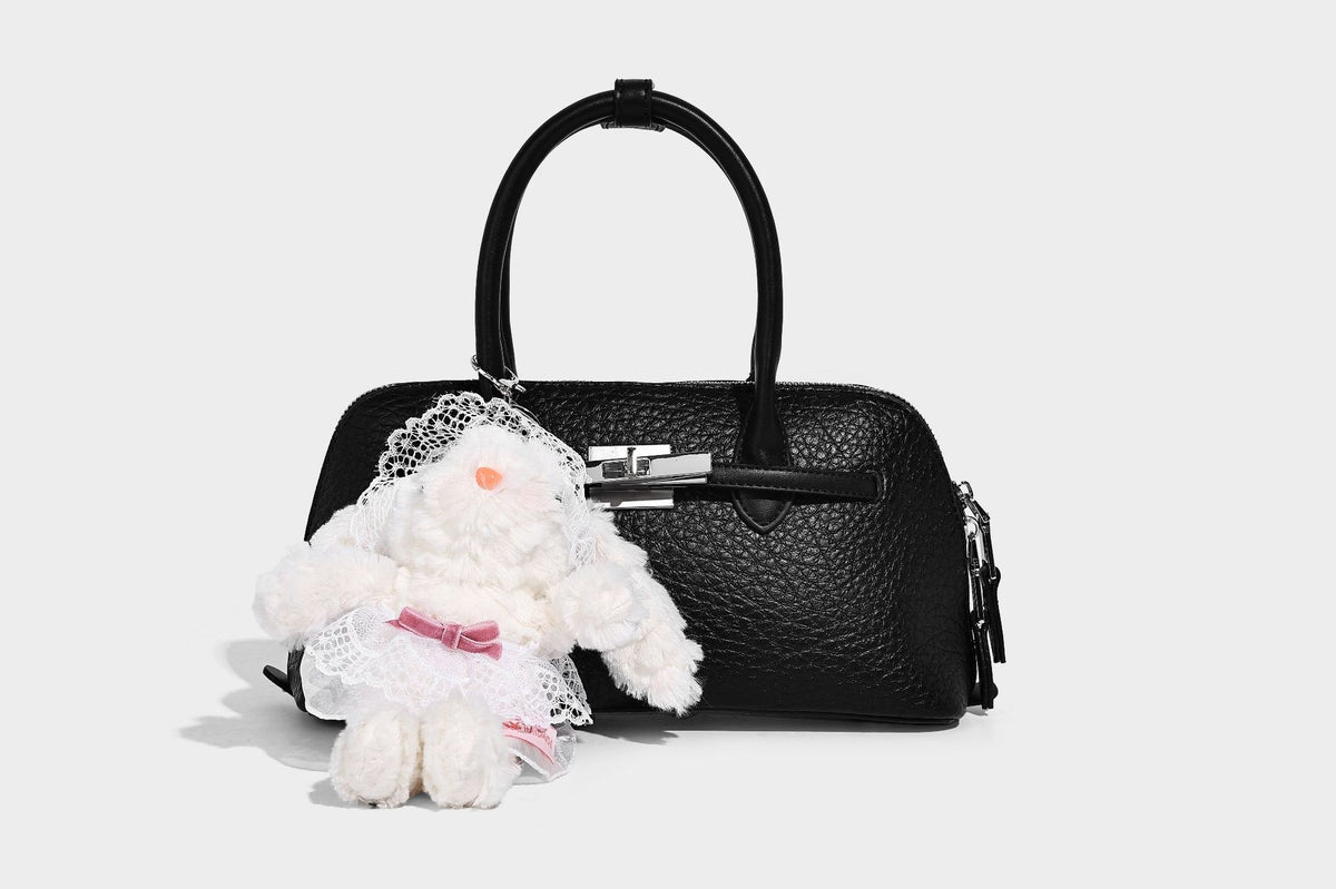 Small structured shell-silhouette top-handle bag with pebbled leather-look finish, silver-tone turn-lock hardware, and