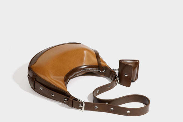 Glossy leather-look crescent hobo shoulder bag with dark contrast trim, silver-tone hardware, and attached mini flap pouch