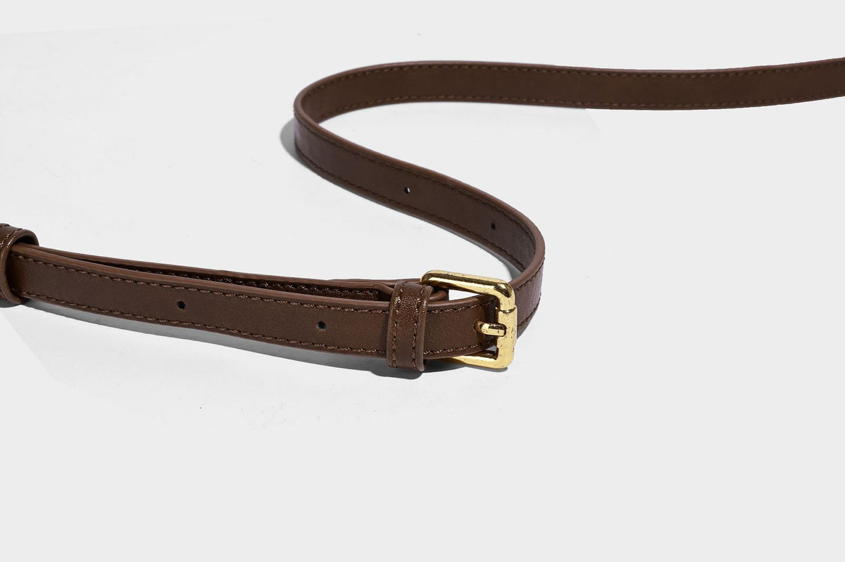 Kompakte Boston-Schultertasche in warmem Braun in Wildlederoptik mit glattem dunkelbraunem Besatz, übergroßen goldfarbenen Ringelementen und Reißverschluss oben