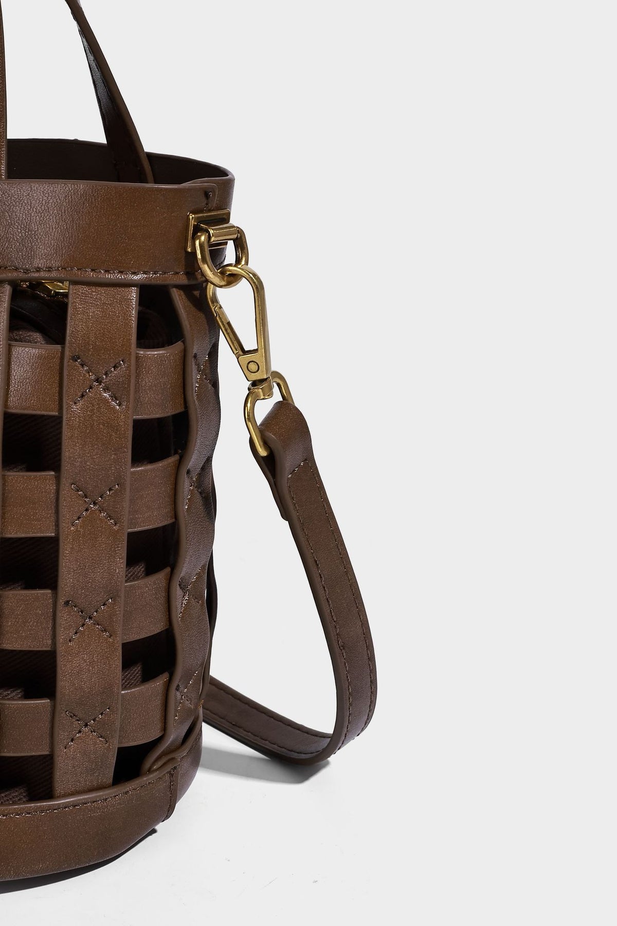 Small woven lattice bucket bag in brown leather-look finish with beaded tassel charm, dual top handles, and detachable