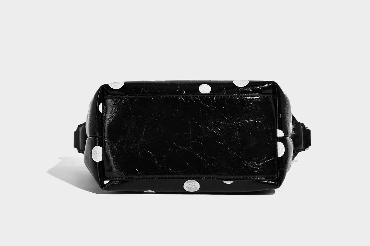Kompakte glänzende Hobo-Schultertasche in Schwarz mit weißen Punkten, Reißverschluss, Beschlägen in Gunmetal und befestigtem Überschlag vorne