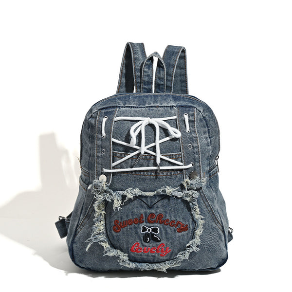 Rucksack aus gewaschenem blauem Denim mit weißer Schnürung auf der Vorderseite, ausgefranstem, herzförmigem besticktem Außenfach und Reißverschluss oben