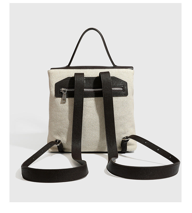 Strukturierter beigefarbener Rucksack aus gewebtem Canvas mit schwarzer Klappe in Lederoptik, Drehverschluss, Tragegriff und flachem Schulter