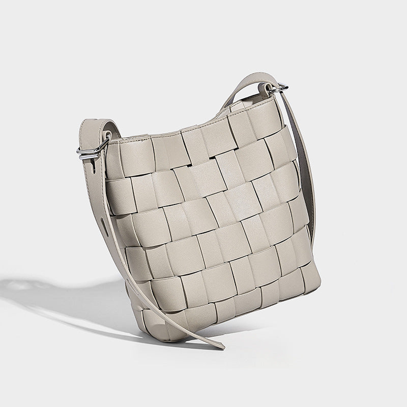 Hand-woven black-and-white checkerboard bucket bag with smooth black trim, silver-tone ring hardware, and adjustable