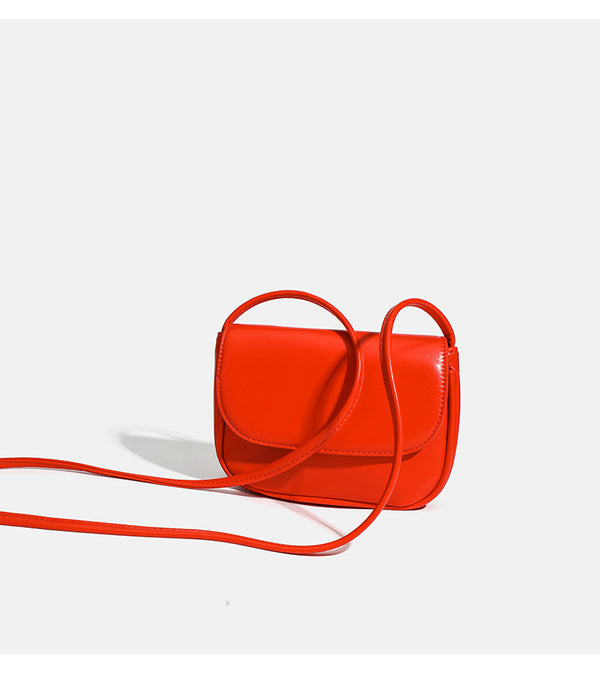 Compact rounded rectangular flap crossbody bag with glossy leather-look finish and long shoulder strap, detail view 11