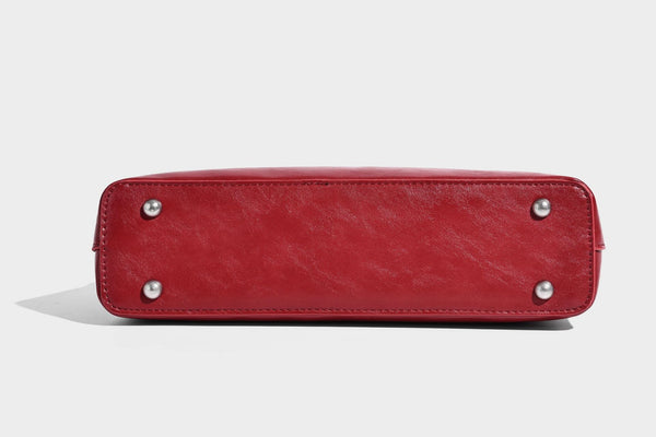 Structured glossy leather-look shoulder bag with wraparound belt straps, silver-tone hardware, and dangling star charm