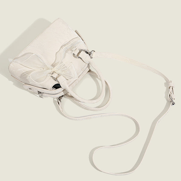 Small structured Boston bag in cream with glossy crinkled finish, sheer bow accent, silver-tone hardware, dual top handles