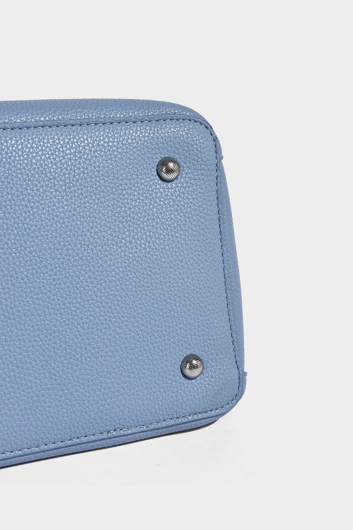 Small structured pebbled bucket tote bag with dual top handles, silver turn-lock front pocket, and detachable shoulder strap