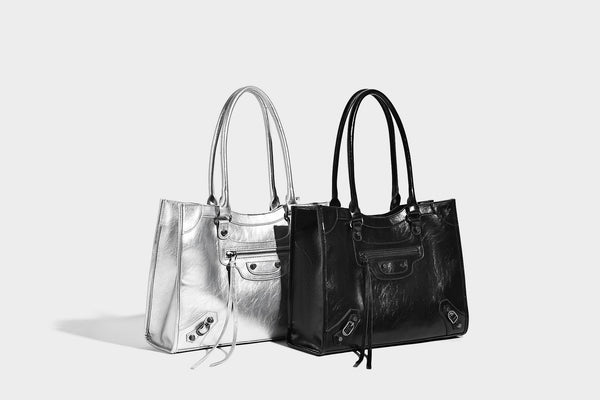 Large structured leather-look tote bag with front zip pocket, moto hardware accents, and long double shoulder straps, detail