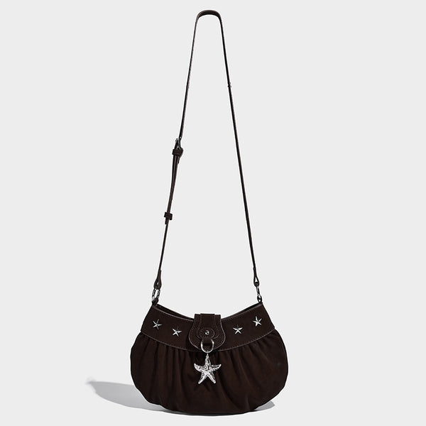 Ruched shoulder bag with curved flap, silver star studs, dangling starfish charm, and adjustable crossbody strap, detail view