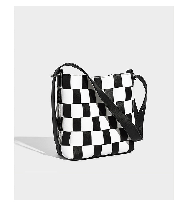 Hand-woven black-and-white checkerboard bucket bag with smooth black trim, silver-tone ring hardware, and adjustable
