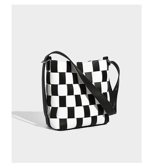 Hand-woven black-and-white checkerboard bucket bag with smooth black trim, silver-tone ring hardware, and adjustable