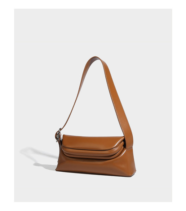 Compact structured baguette shoulder bag with smooth leather-look finish, zip top, and adjustable silver-buckle strap, detail