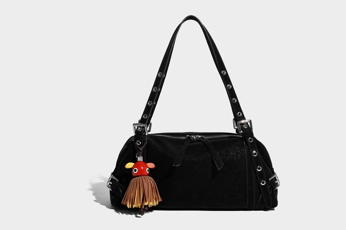 Weiche, zylinderförmige Schultertasche in Dunkelbraun mit silberfarbenen Riemen mit Ösen, Reißverschluss oben, seitlichen Schnallenbeschlägen und Quaste