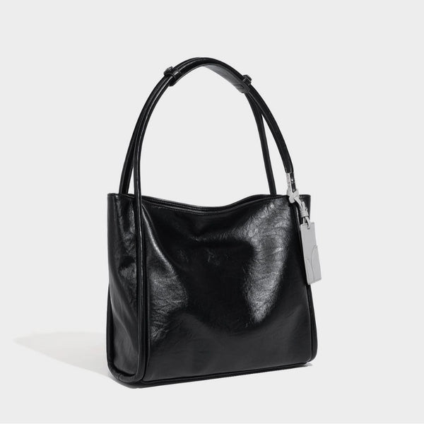 Schwarze, glänzende Shopper-Tasche in Lederoptik mit zwei runden Tragegriffen und silberfarbenen Beschlägen, Vorderansicht