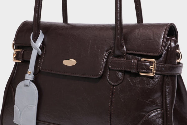 Structured glossy leather-look satchel bag with flap closure, gold-tone buckle accents, double top handles, detachable