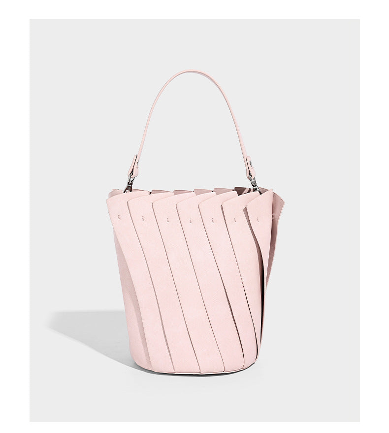 Structured pleated-panel bucket bag with curved top handle and detachable adjustable shoulder strap in smooth matte, detail