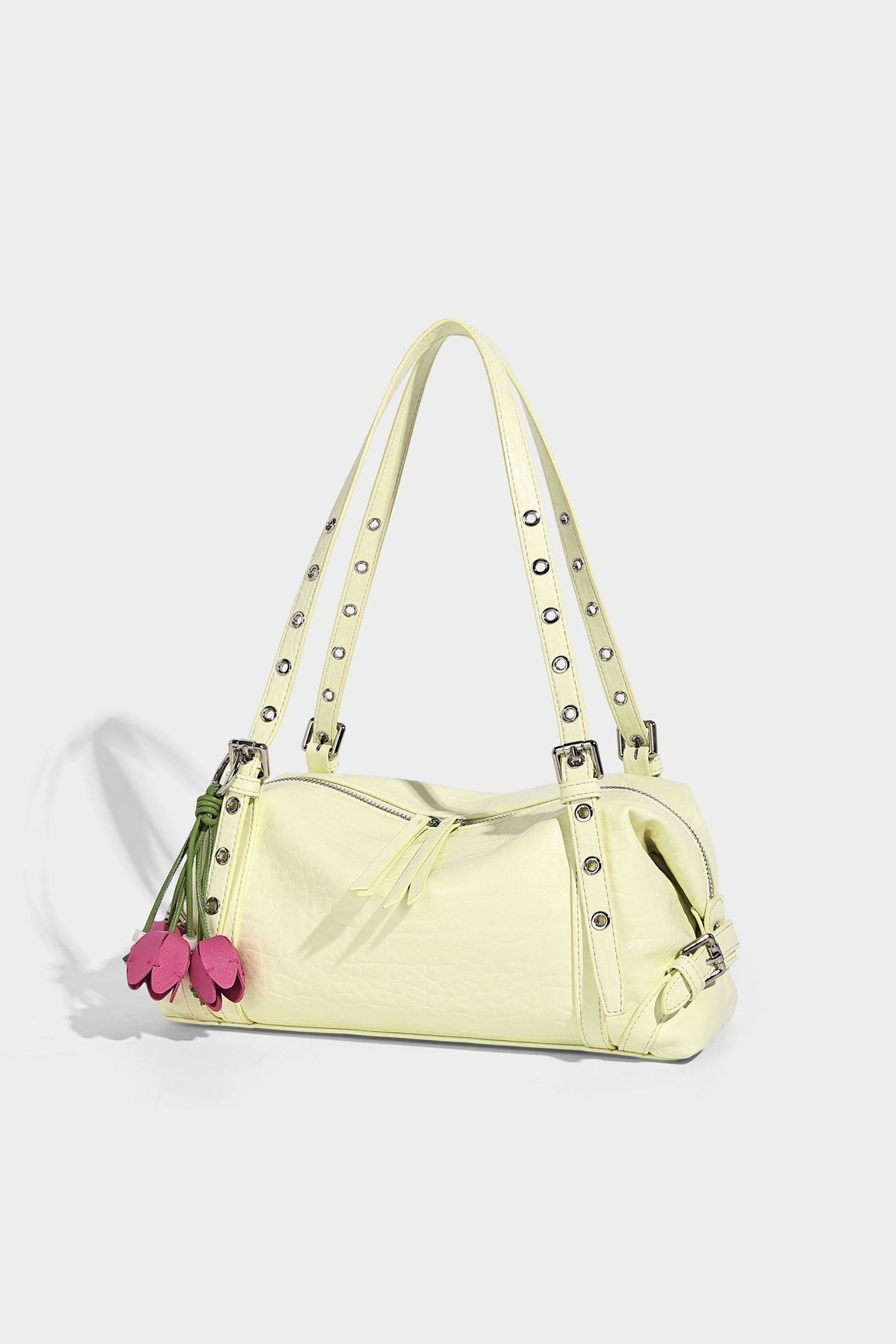Pale yellow leather-look barrel bag with silver grommet-studded shoulder straps, top zip closure, and pink tulip floral