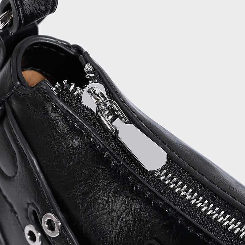Compact moto-inspired shoulder bag with crisscross grommet strap detail, glossy textured finish, and adjustable crossbody