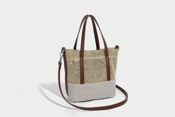Two-tone open-weave tote bag in beige and cream with brown leather-look handles, tassel bead charm, and detachable