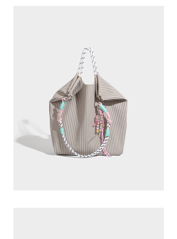 Slouchy pinstripe tote bag with braided rope handles, metal ring hardware, and colorful knotted rope charm, detail view 12