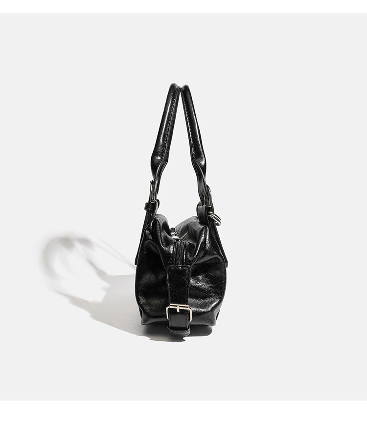 Compact black glossy leather-look satchel bag with silver-tone rivets, buckle hardware, and dual padded top handles, detail