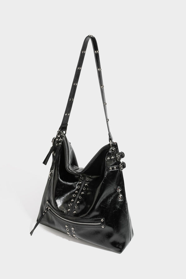 Black glossy leather-look slouchy shoulder bag with silver stud and eyelet hardware, top zip closure, front zip pocket, and