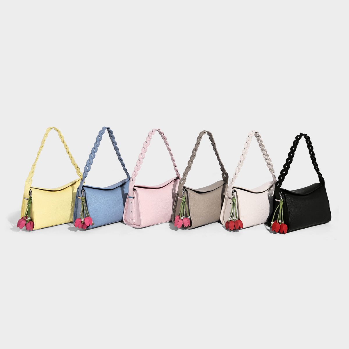 Small structured pebbled-finish shoulder bag with braided top handle, detachable crossbody strap, floral tassel charm, and